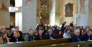 Synodaalikokouksen iltapäivän messu alkamassa Lohjan Pyhän Laurin kirkossa, pappeja istumassa kirkonpenkissä