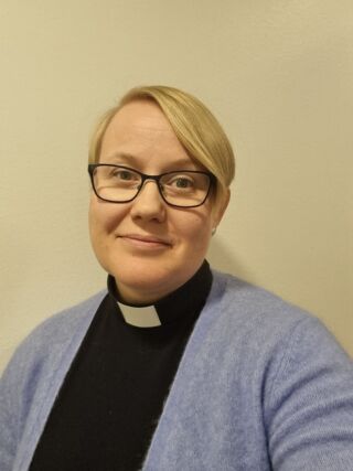 Kasvokuva pastori Kaisa Yletyisestä papinpaidassa ja vaaleansinisessä villatakissa