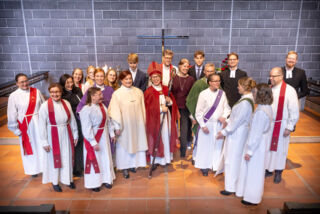 Kuvassa pappis- ja diakonianvirkaan 16.11.2025 vihittyjä Tapiolan kirkon alttarin edessä puolikaaressa, keskellä piispa Kaisamari Hintikka ja takarivissä juhlamessun avustajat